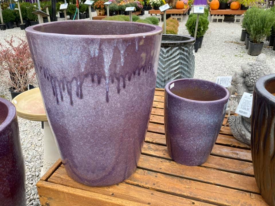 Set of two flower pots, both gradient purple colors, one large, one medium, displayed on a wooden shelf at Full Features Garden Center. Background includes various other pots, plants and Fall decor including pumpkins.